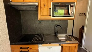 Een praktische keuken met een inbouwmagnetron, een kookplaat en een spoelbak.