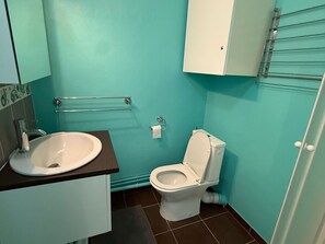 Un baño con inodoro blanco, lavamanos y toallero.