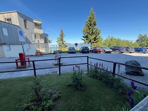 Uma área de estacionamento com carros, um edifício com uma placa e vista para a montanha.