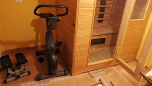 Kuntosali, jossa on kuntoiluvälineitä, puuseinät ja laattalattia.