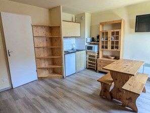 Une cuisine avec des meubles de rangement en bois, un four à micro-ondes, un évier et une table à manger.