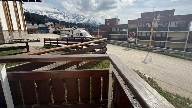 Une vue d’un parking avec une clôture en bois, un panneau indiquant qu’il est interdit de se garer, et une montagne en arrière-plan.