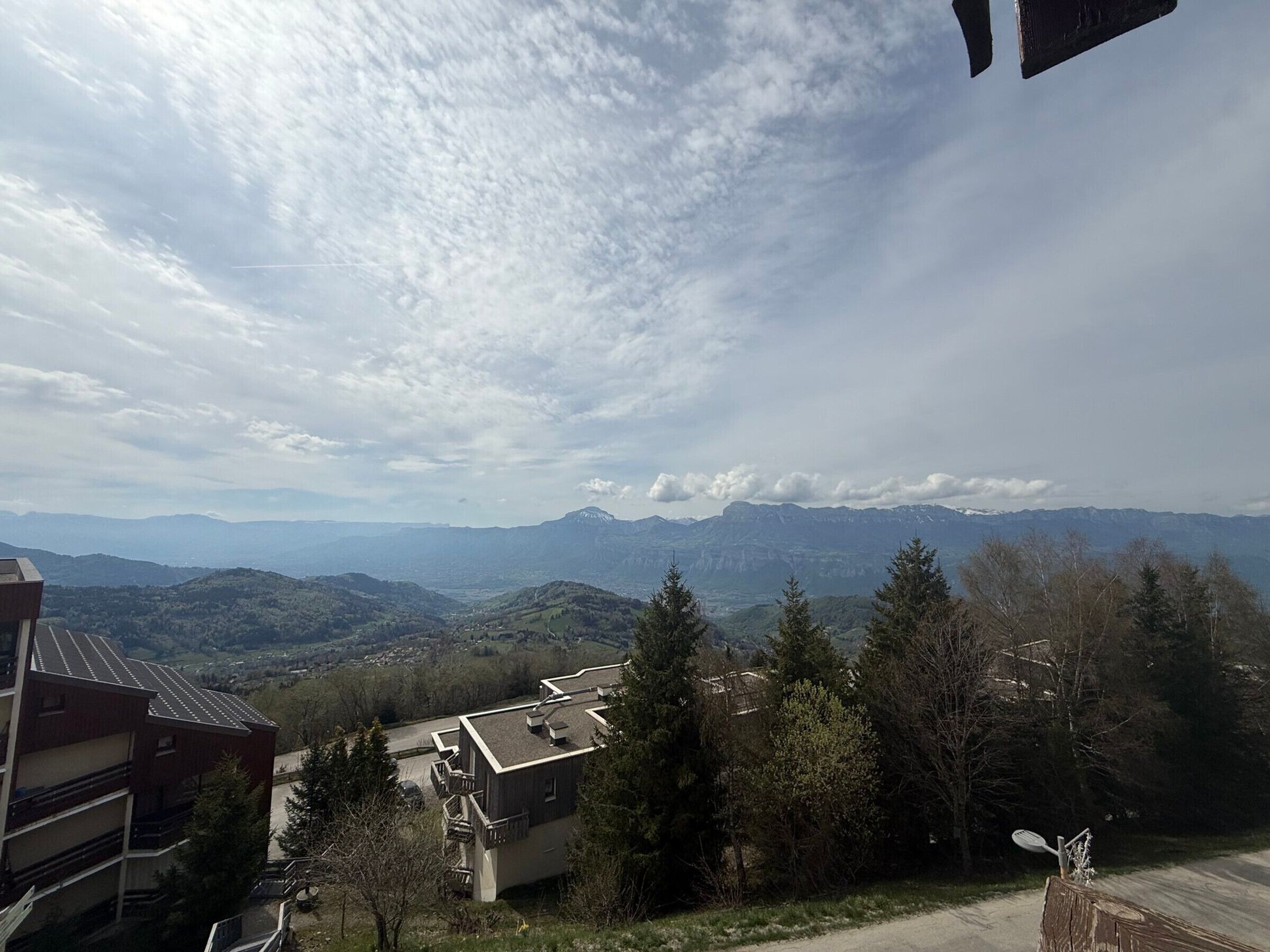 Gebirgslandschaft mit einem Gebäude im Vordergrund und einer Straße, die darauf zuführt.