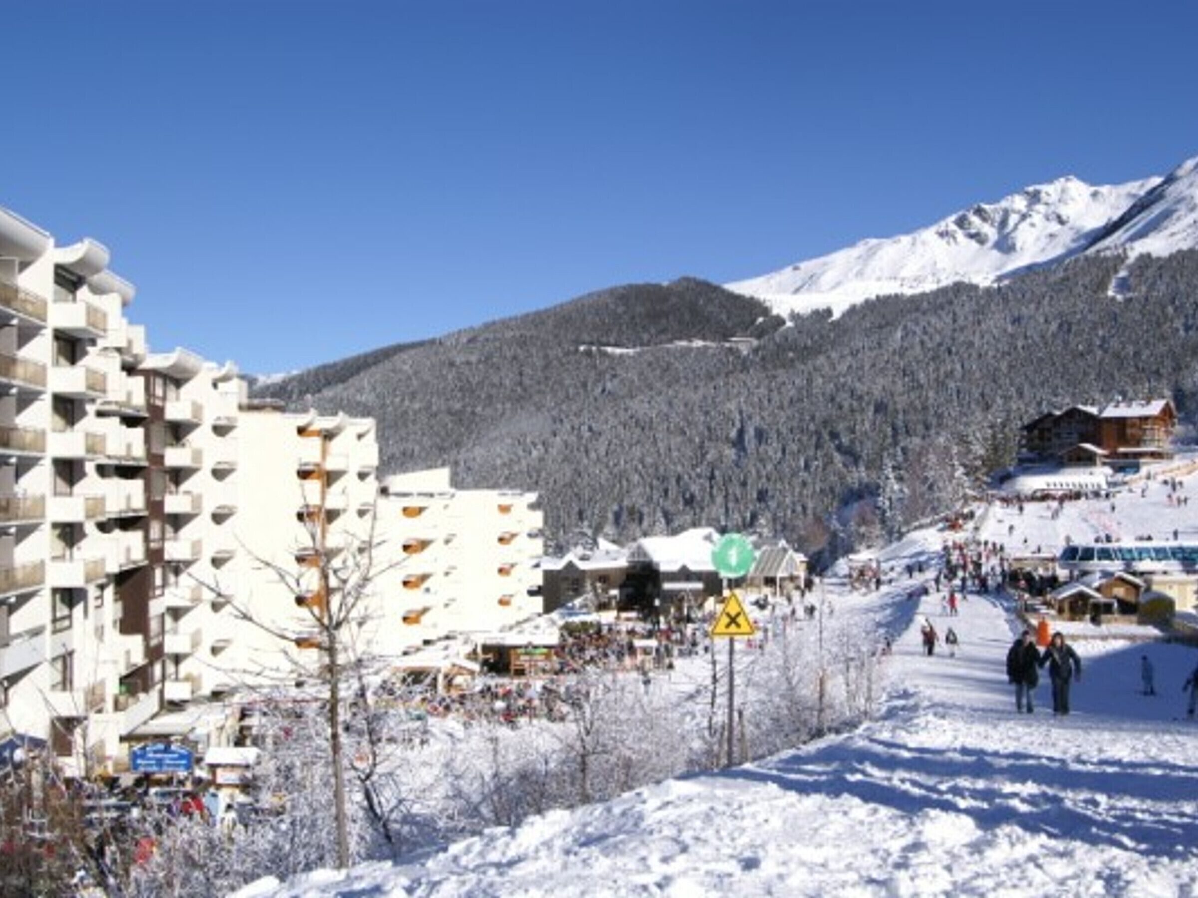 A snow-covered mountain town with a ski resort, buildings, and a clear sky.