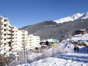 A snow-covered mountain town with a ski resort, buildings, and a clear sky.