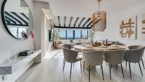 Een moderne eetruimte met een ronde tafel, grijze stoelen en een hanglamp.