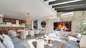 Een moderne woonkamer met een open haard, eethoek en keuken.
