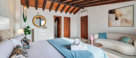 Une chambre d’hôtel avec un lit, un canapé, un miroir rond et des portes en bois.