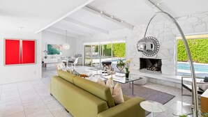 Un ampio soggiorno dal design moderno, con divano, camino e una grande finestra vista verde.