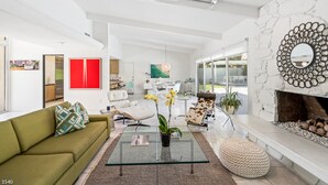 Un soggiorno moderno con un divano verde, un tavolino in vetro e un caminetto con specchi decorativi.
