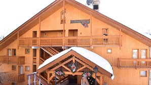 A wooden chalet with a balcony, a staircase, and a sign reading "Hotel Grand Göstern".