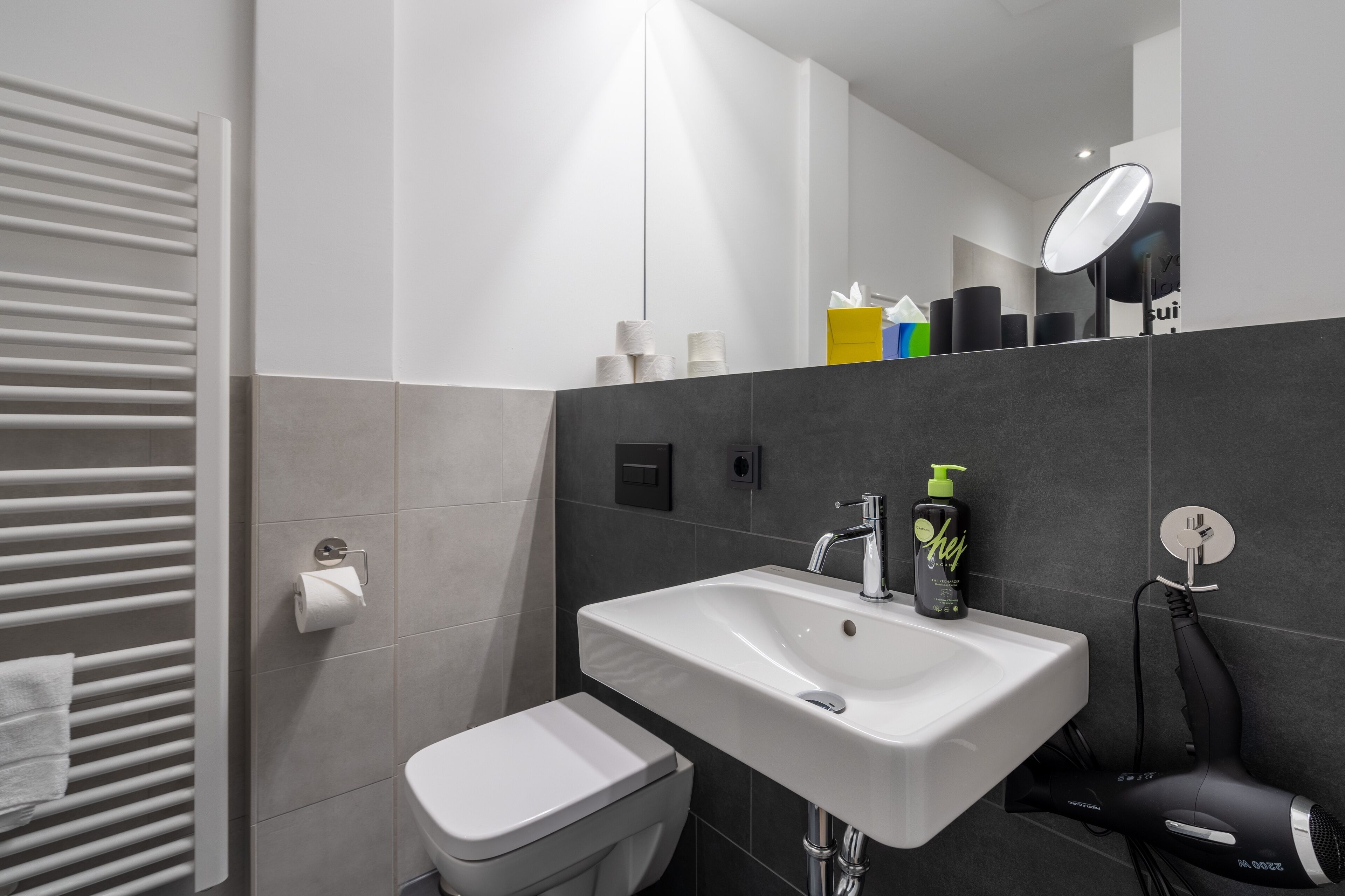 Une salle de bain moderne avec un lavabo blanc, des toilettes et un porte-serviettes.