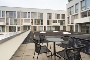 Une terrasse sur le toit, dotée d’un espace extérieur aménagé et offrant une vue sur un bâtiment moderne.