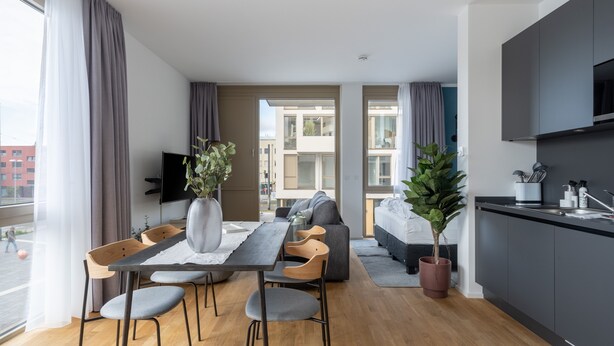 Un apartamento moderno con comedor, sofá, cocina y ventanas amplias.