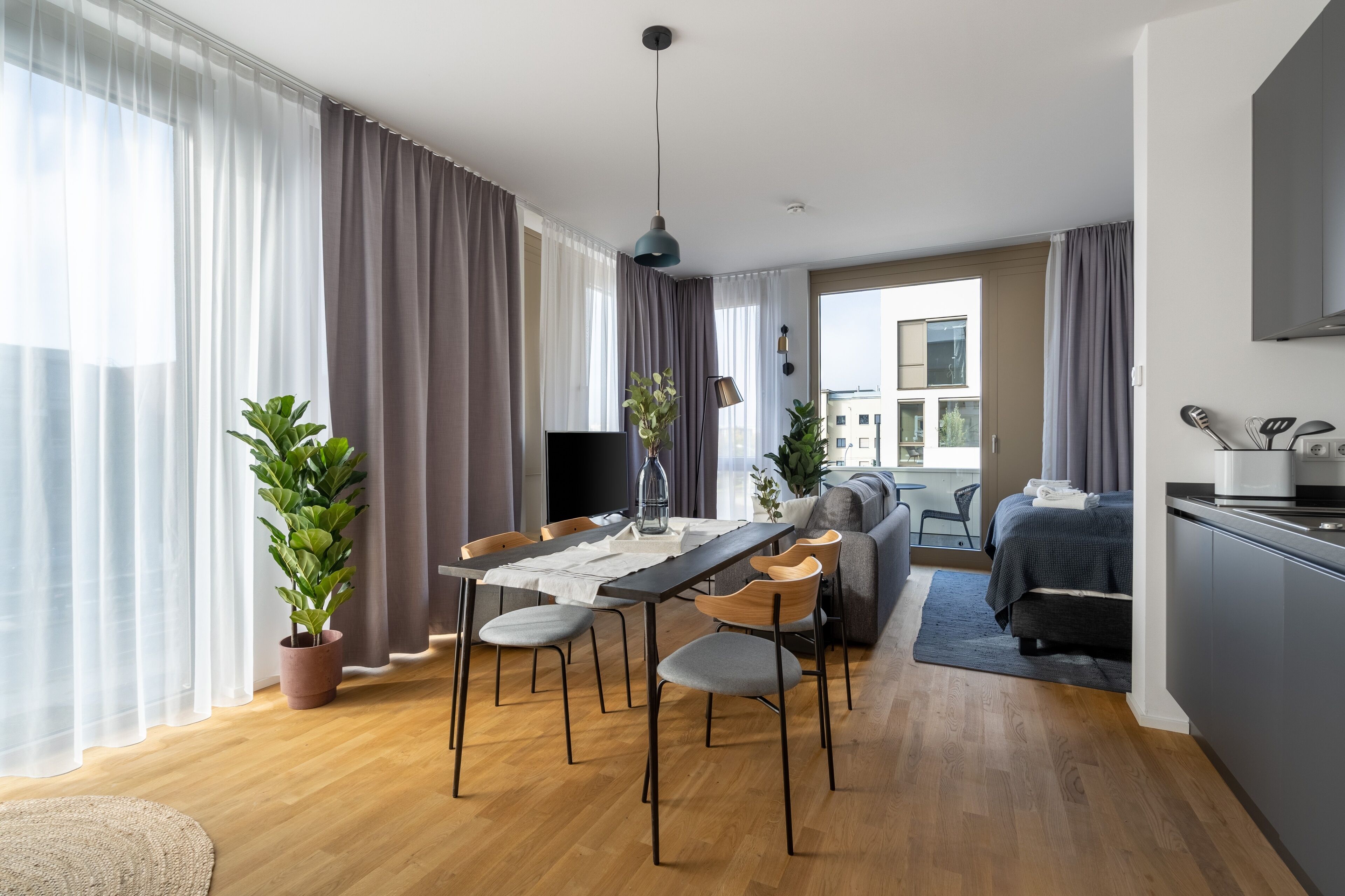 Una sala de estar moderna con comedor, sofá, cama y cocina.