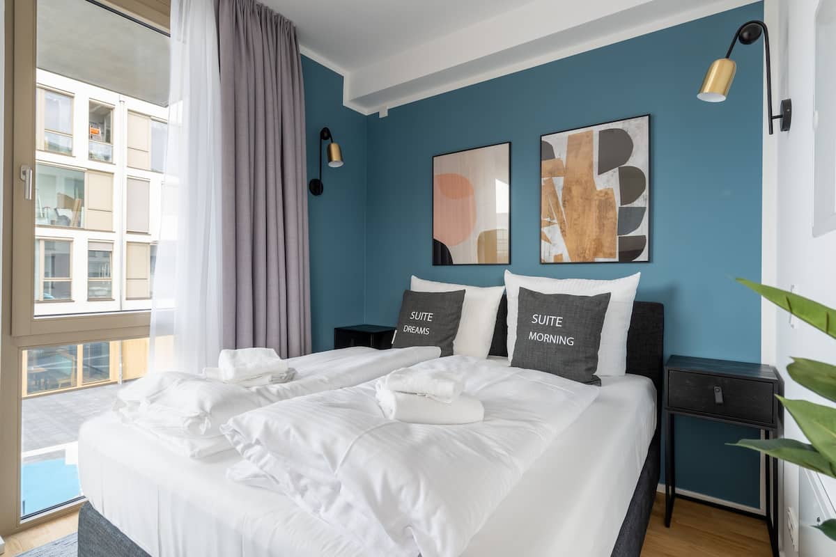Habitación de hotel con una cama grande, dos mesitas de noche y vistas al exterior.