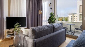 Una sala de estar moderna con un sofá gris, un televisor de pantalla plana, una mesita y una planta en maceta.