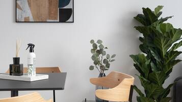 Un comedor moderno con una mesa, sillas, una planta en maceta y una obra de arte abstracto enmarcada en la pared.