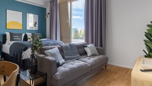 Un dormitorio moderno con sofá, cama y un amplio ventanal con cortinas.