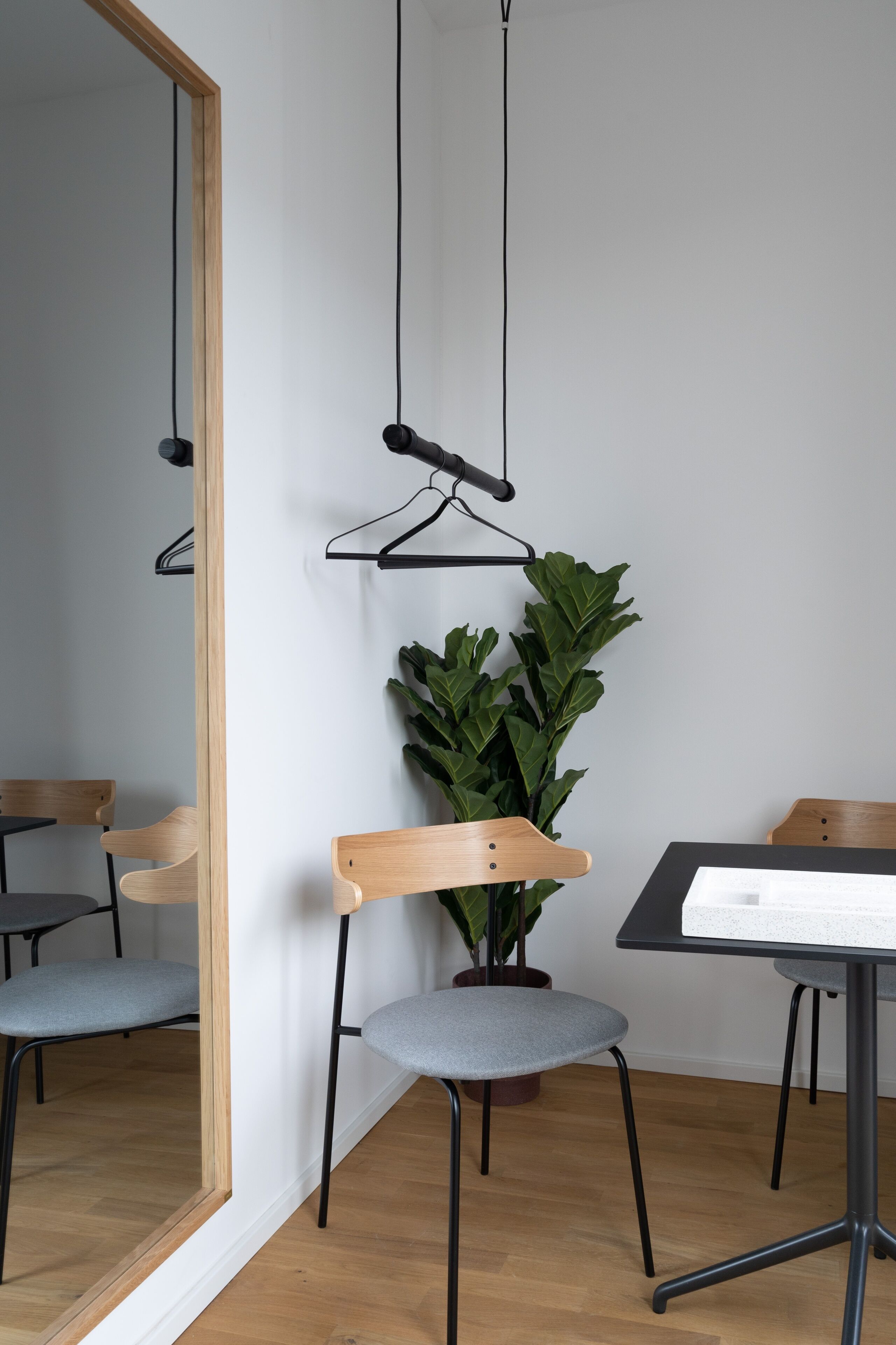 Une chambre moderne avec un miroir à cadre en bois, une plante en pot et une table à la surface noire.