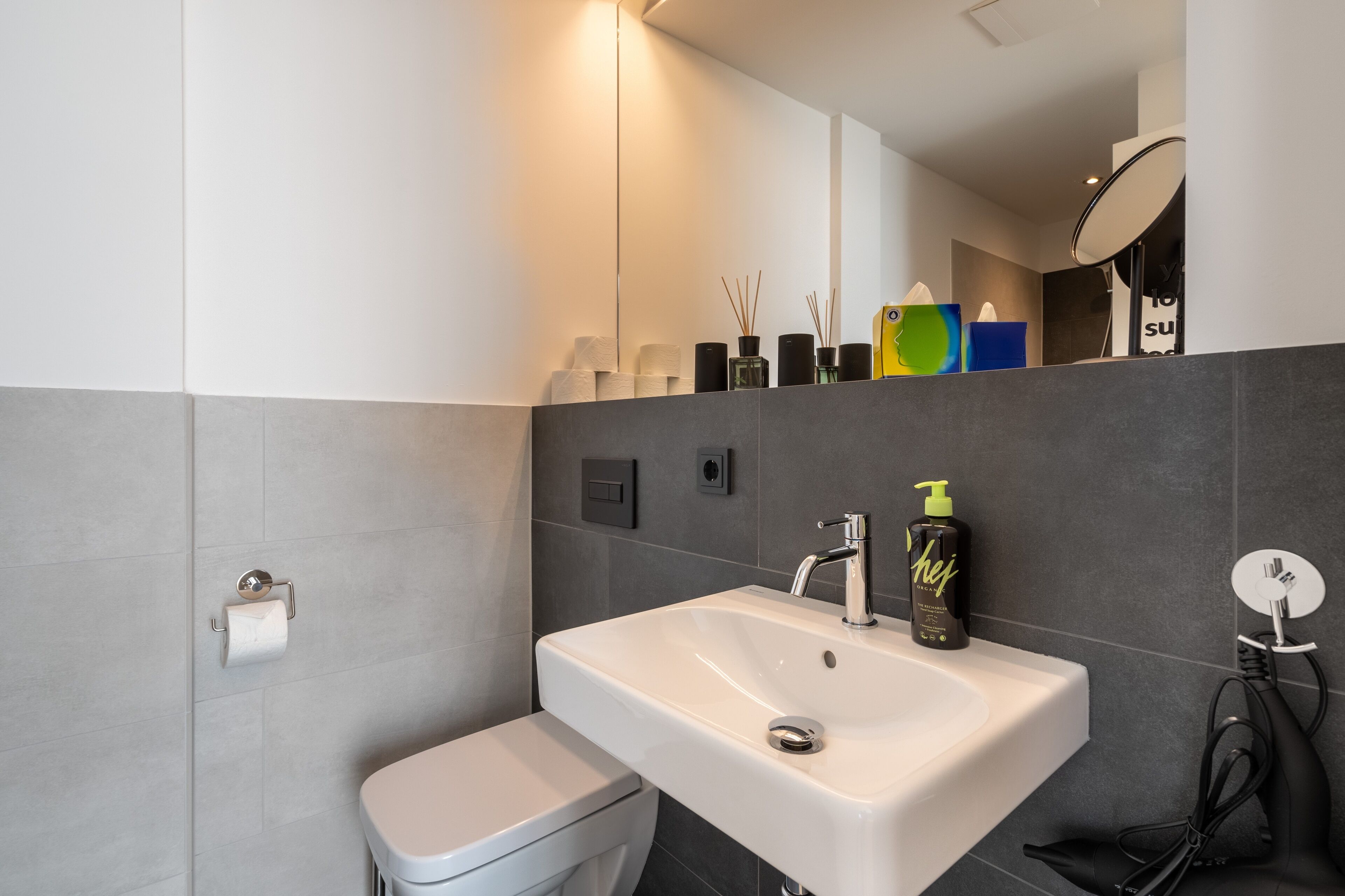 Un baño moderno con lavamanos blanco, inodoro y espejo.