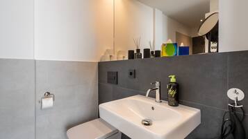 Un baño moderno con lavamanos blanco, inodoro y espejo.