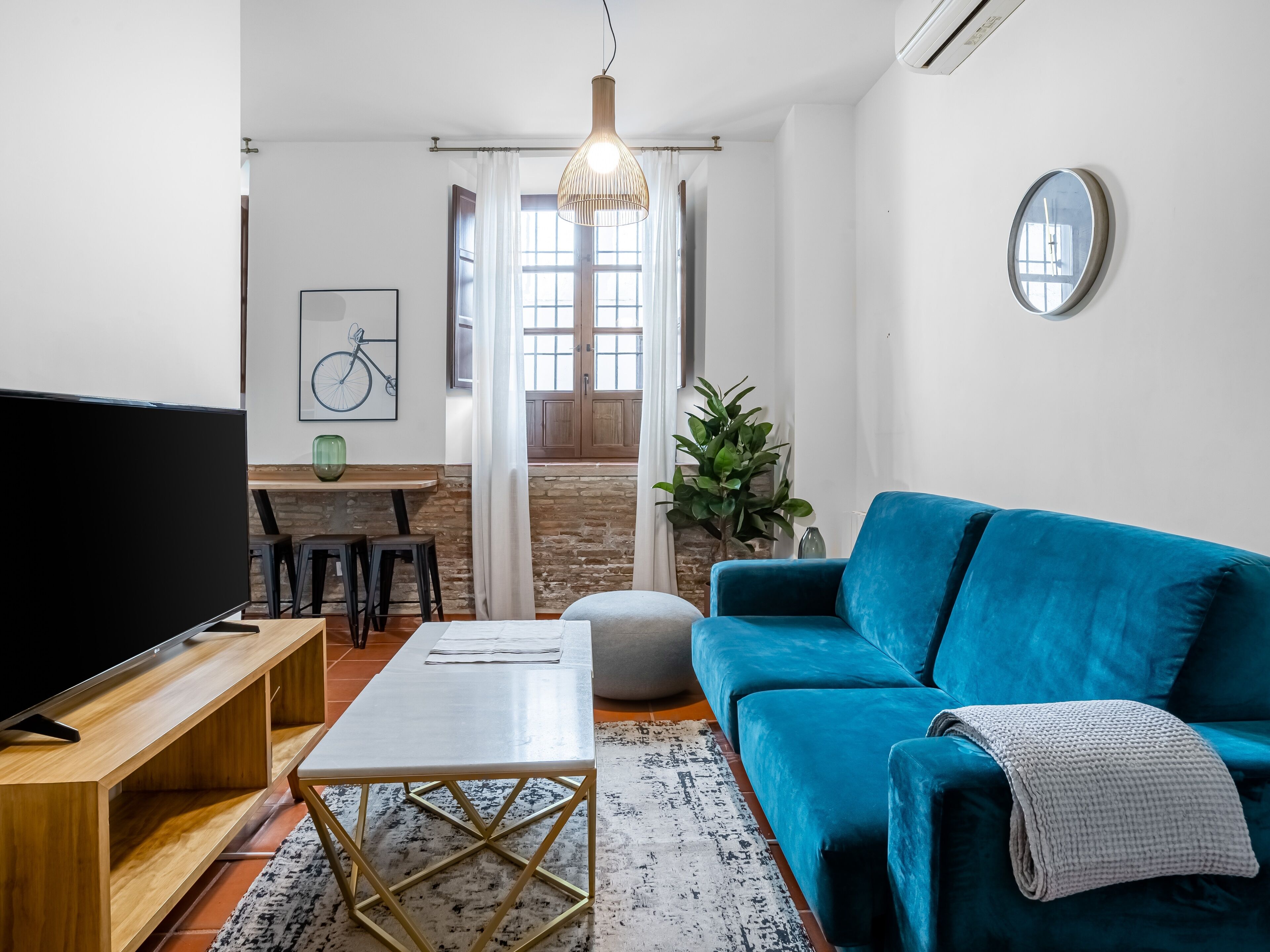 A modern living room with a blue sofa, a coffee table, a TV, and a dining area with a table and chairs.