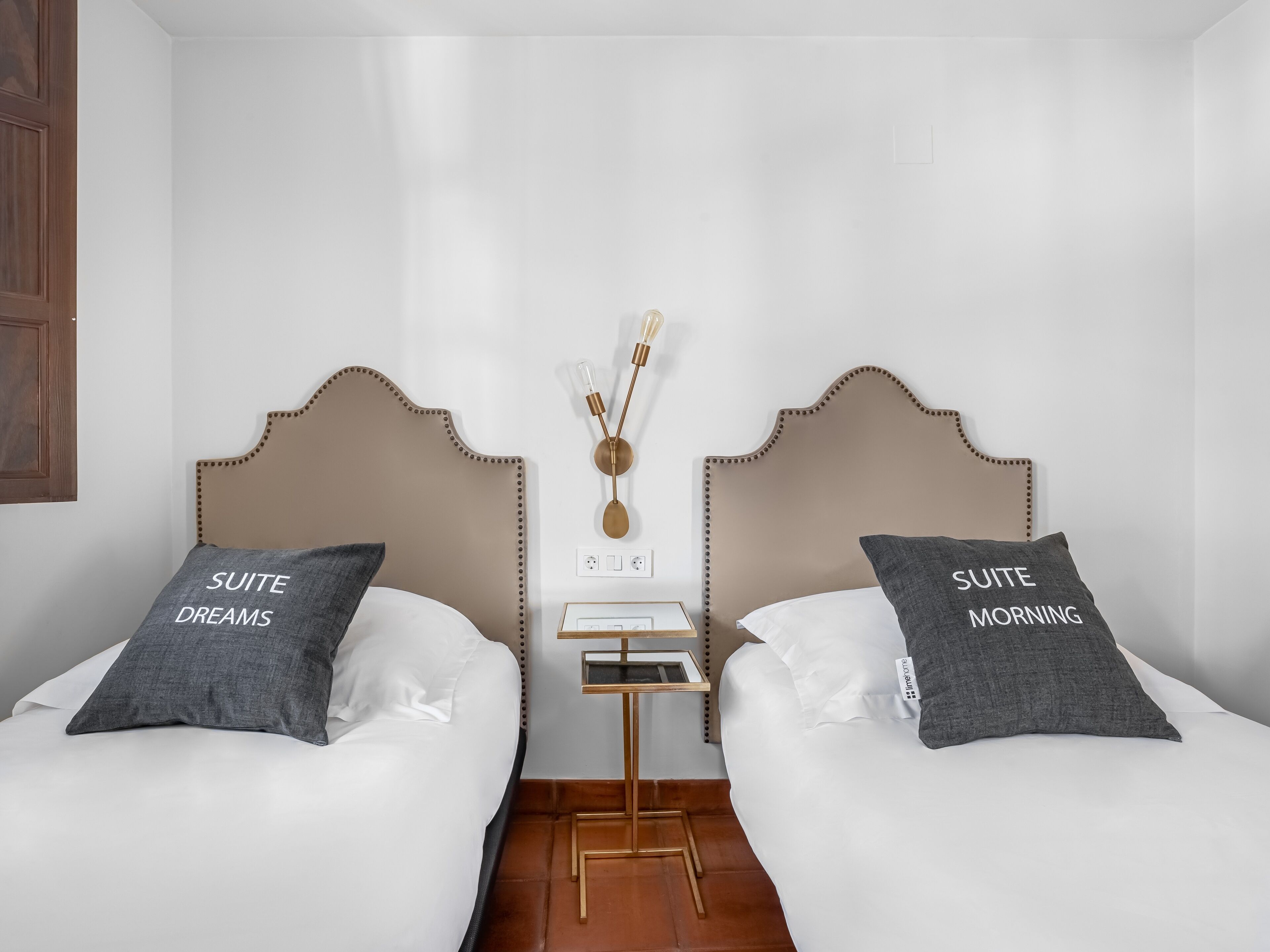 A hotel room with two beds, each with a headboard and pillows labeled "SUITE DREAMS" and "SUITE MORNING".