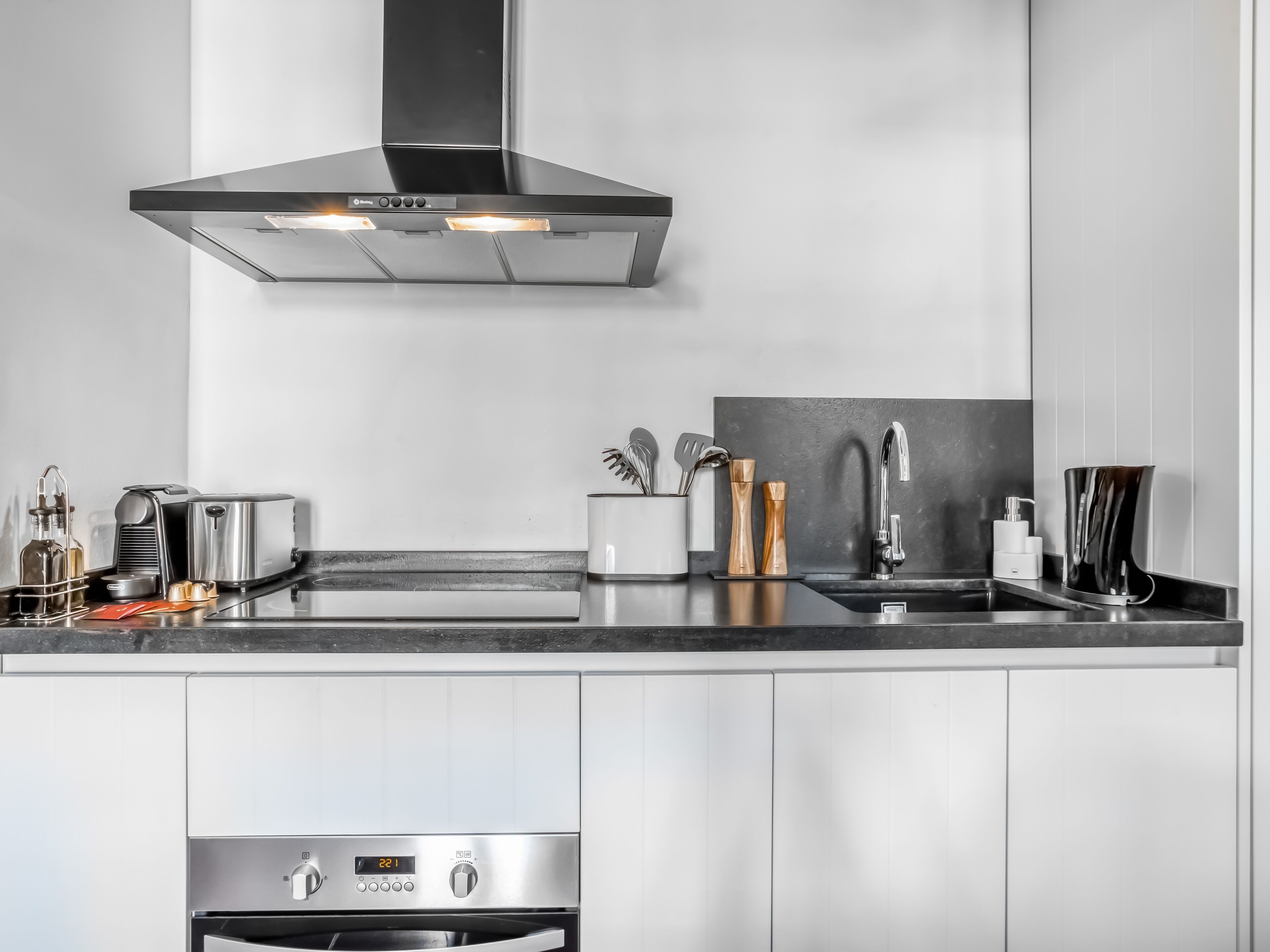 Una cocina moderna con electrodomésticos de acero inoxidable, horno empotrado y un elegante salpicadero.