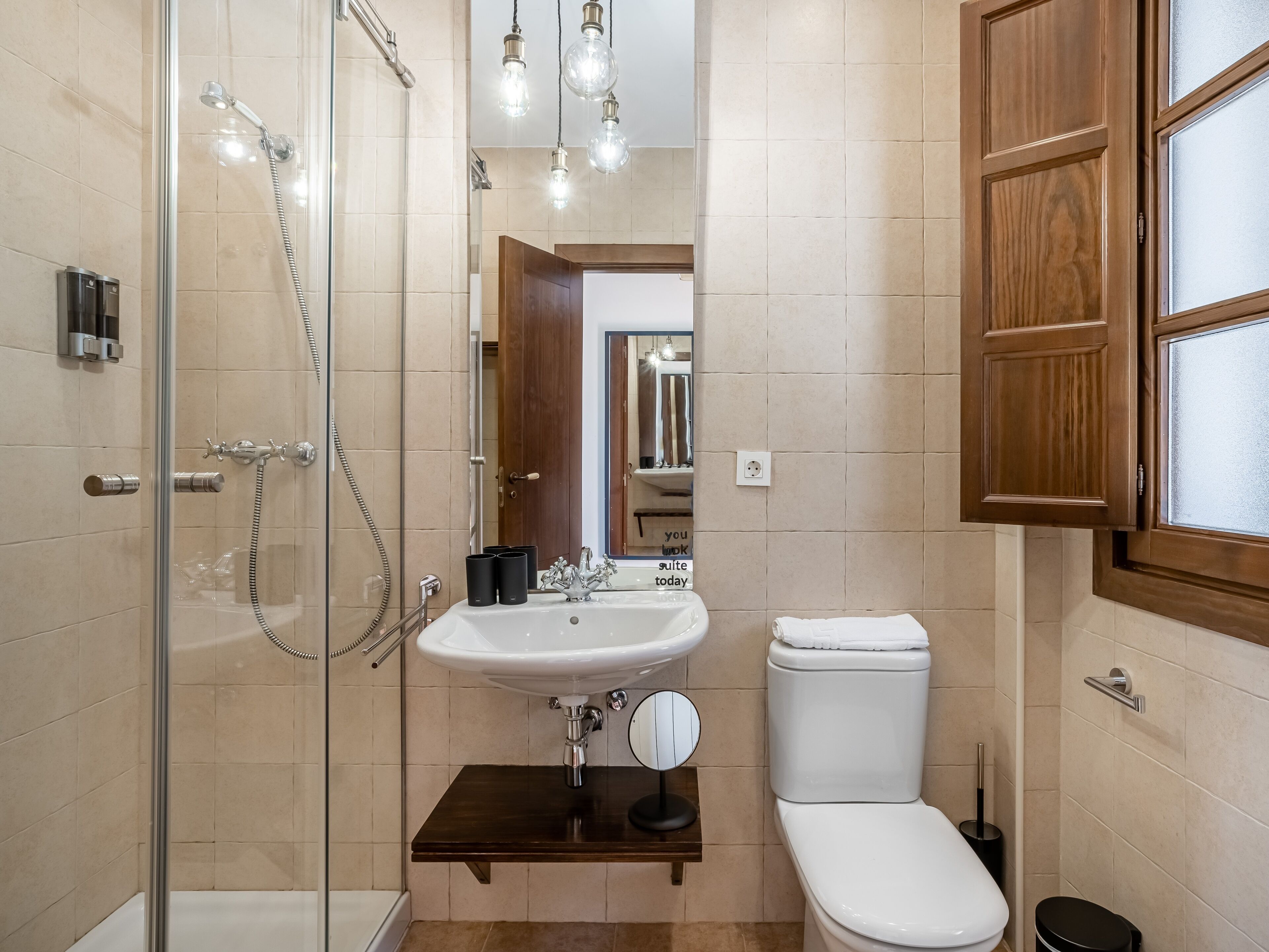 A modern bathroom with a glass-enclosed shower, a white sink, and a toilet.