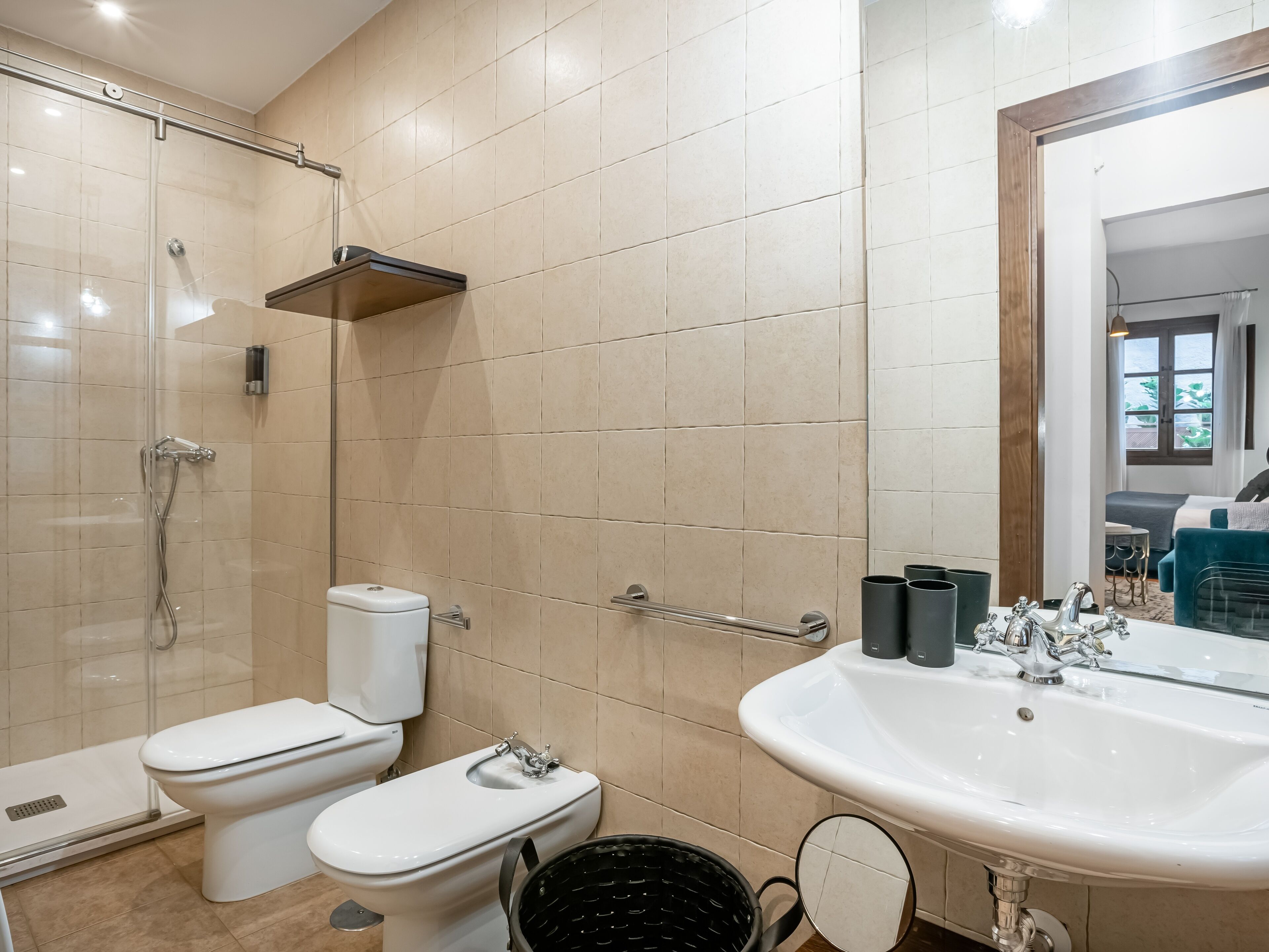 Un baño moderno con cabina de ducha de vidrio, inodoro, lavamanos con espejo y ventana con vistas al exterior.