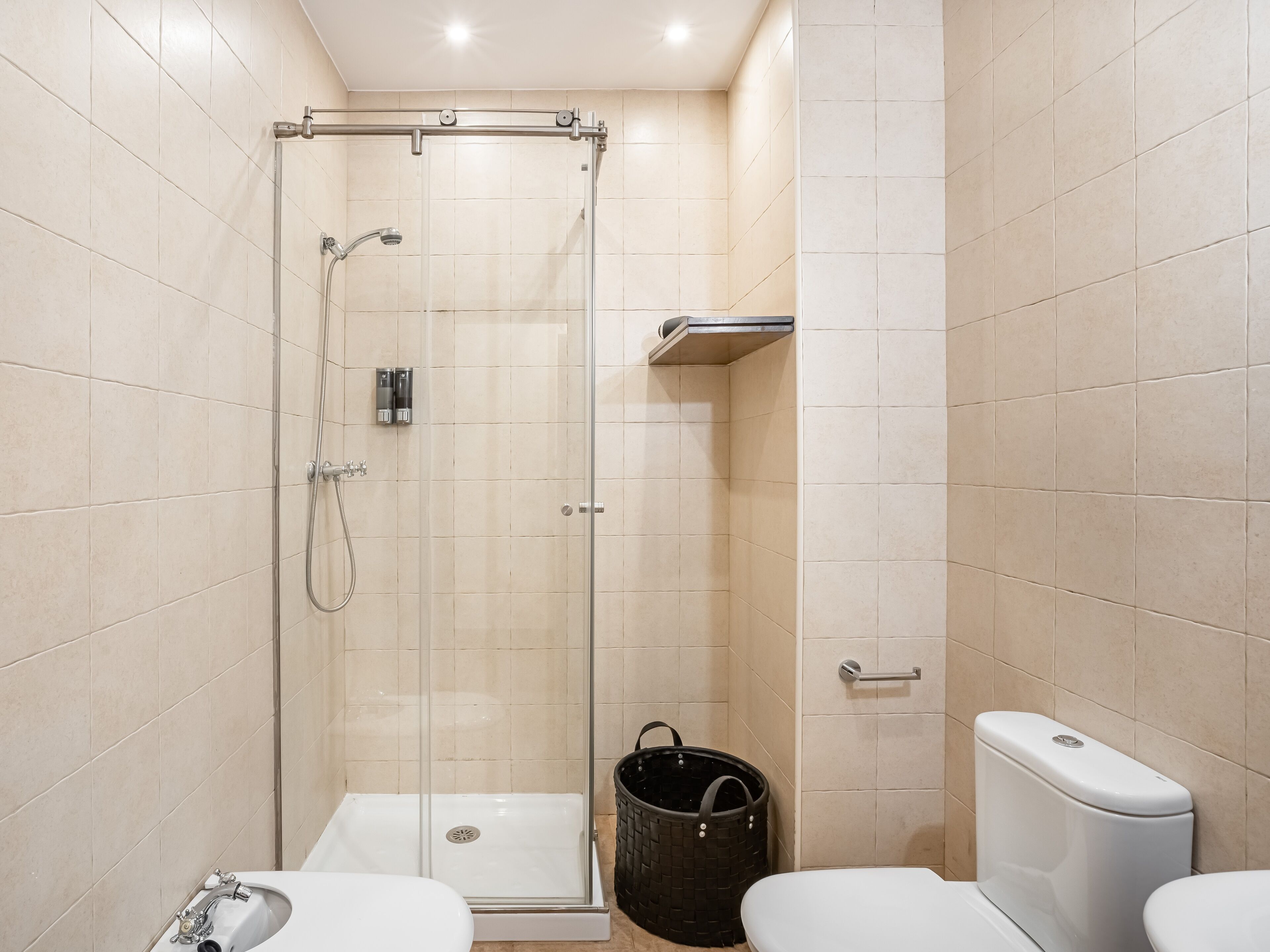 A modern bathroom with a glass-enclosed shower, a white sink, and a toilet.
