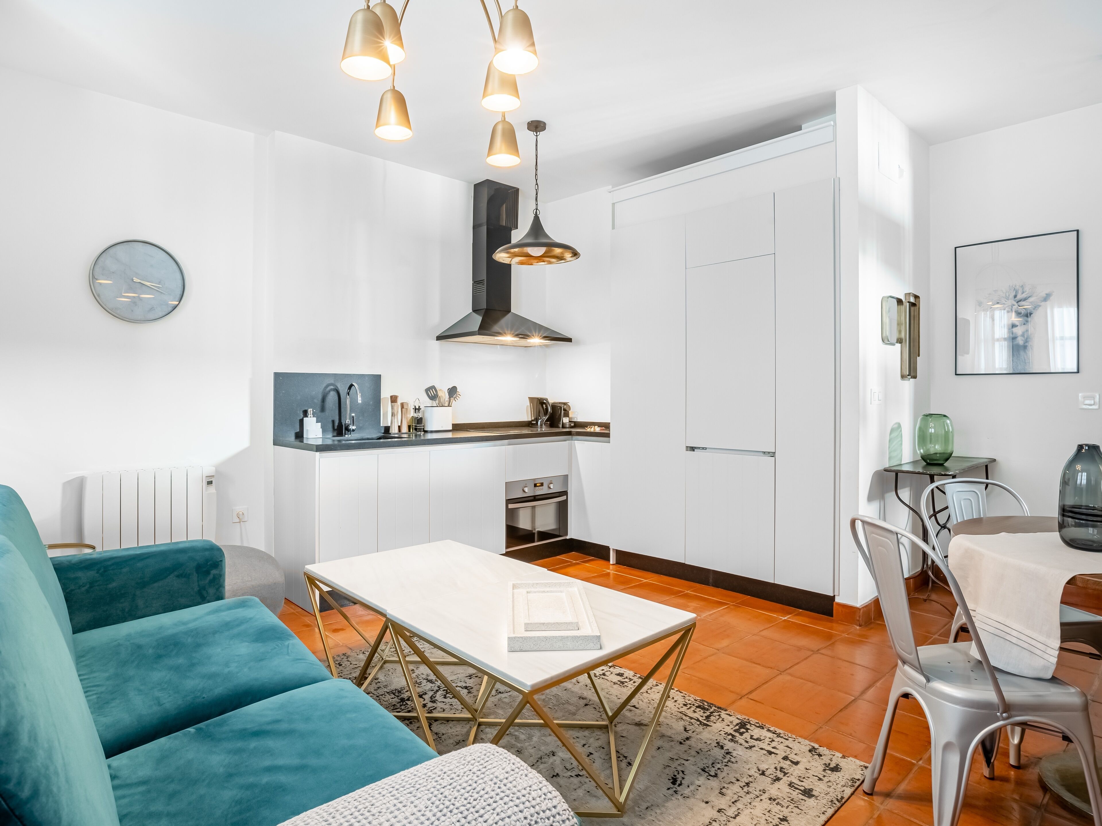 A modern kitchen with white cabinets, a built-in oven, and a dining area with a table and chairs.