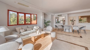 Un salon moderne comprenant un canapé, des fauteuils, une table basse et un coin repas avec une table et des chaises.