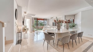 Un espace repas moderne avec une table ronde, des chaises grises et des plantes en pot.