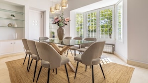 A modern dining area with a glass table, six chairs, and a vase of flowers. - ELEGANT VILLA FOR GOLFERS: OUTDOOR BBQ, POOL AND SOLARIUM, PLUS HOME CINEMA ROOM (San Pedro de Alcántara)