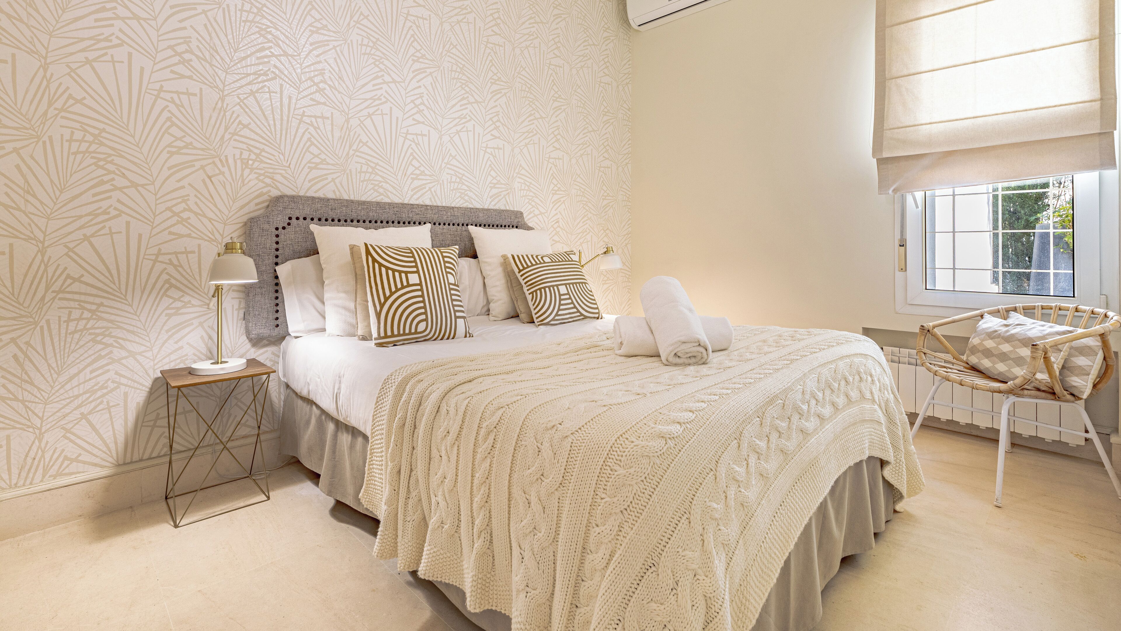 A bedroom with a bed, bedside tables, a lamp, a window, and a chair.