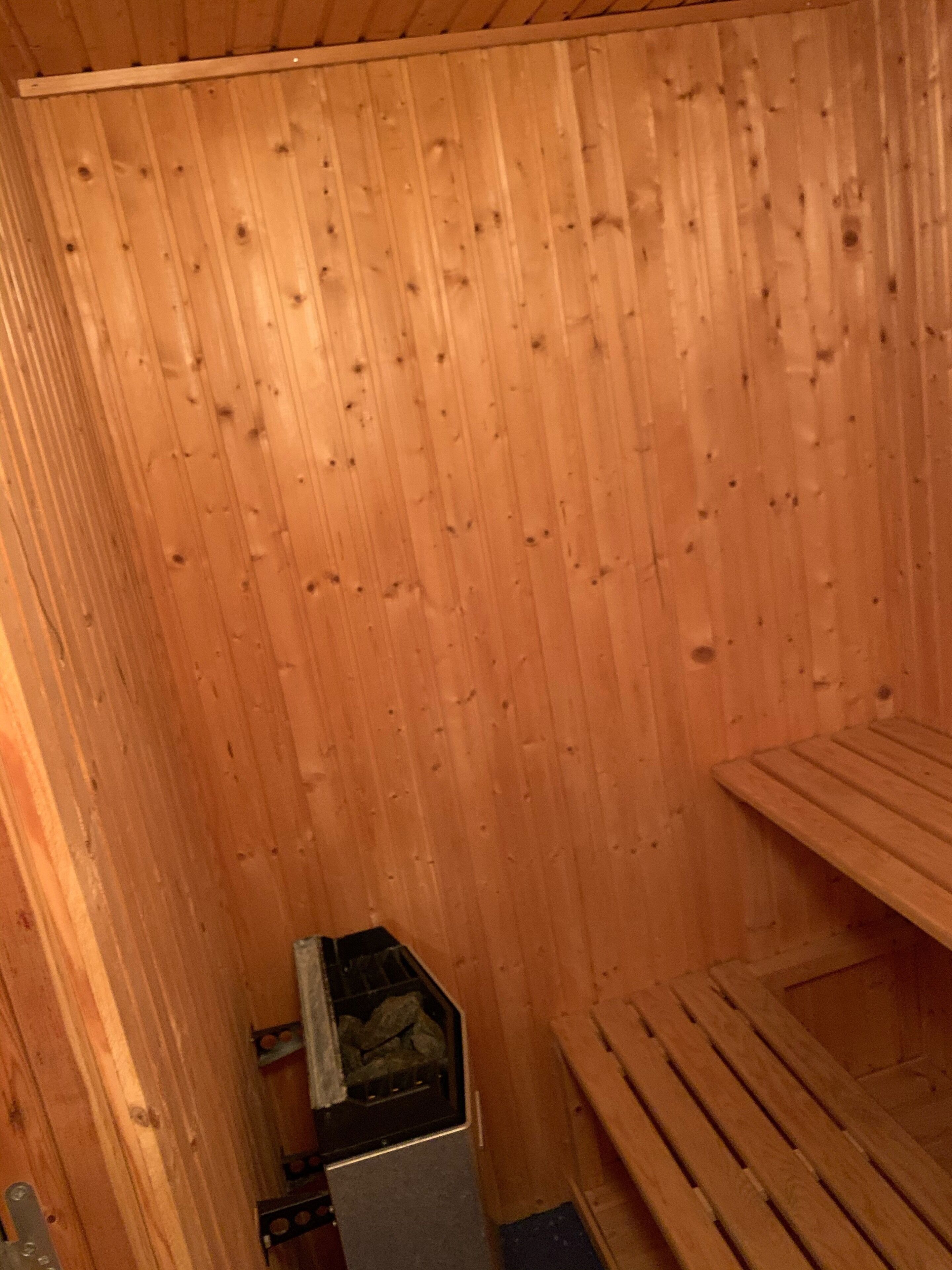 A wooden sauna room with a bench and a sauna heater.