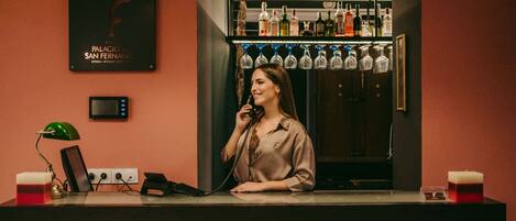 A bar area with a counter, a refrigerator stocked with bottles, and a wall-mounted sign.