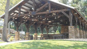 A covered pavilion with a metal roof and stone pillars, featuring picnic tables and benches. - Bluff Cabin #4 Lake Retreat, Lake Views & a Relaxing Hot Tub, NO pet cabin (Kimberling City)