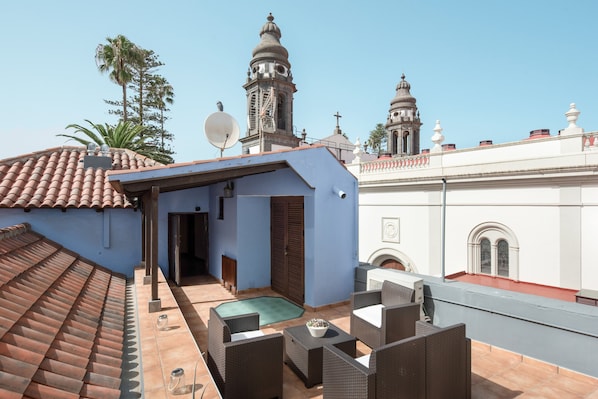 A rooftop patio with wicker furniture, a satellite dish, and a view of a church with domes.