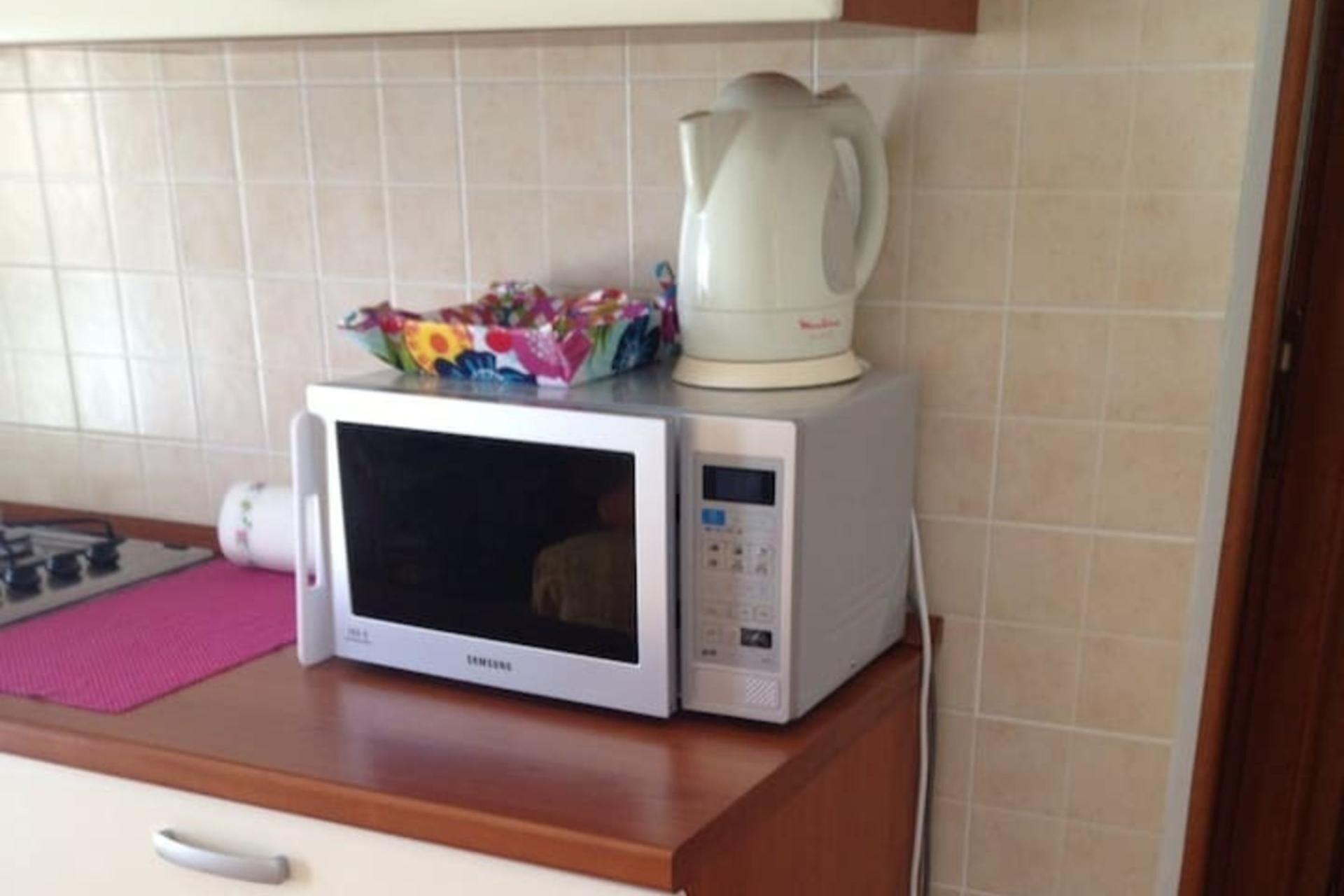 A microwave oven with a digital display and control panel, placed on a wooden countertop.