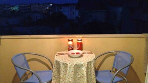 A balcony with a table set for two, two chairs, and two candles. - Serenity Escape in Marina Di Caulonia (Caulonia)