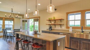 A modern kitchen with a large island, bar stools, pendant lights, and wooden shelves. - Poolside Cabin #11 (3 bedroom cabin, Modern, Scenic Views, oversized deck.) (Kimberling City)