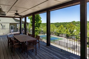 Ein überdachter Außenbereich mit Tisch und Stühlen, einem Pool und Blick auf eine grüne Landschaft.