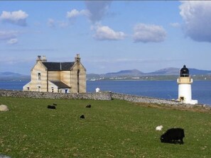 A coastal building with a lighthouse in the background.