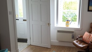 Une chambre à coucher avec un lit, une fenêtre donnant sur un paysage agréable, un radiateur et une porte.