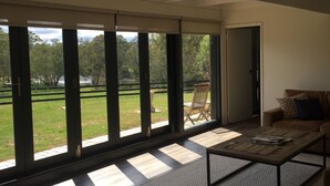 A room with large windows, a wooden floor, a sofa, and a coffee table.