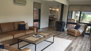 A spacious living room with a brown leather sofa, a wooden coffee table, and a fireplace.