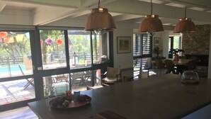 A spacious kitchen with a large island, pendant lighting, and a view of an outdoor pool area.